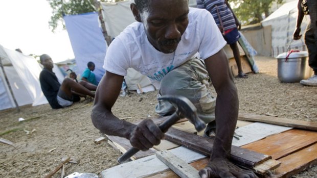 Moving to the recovery stage ... a man builds floorboards for a tent in a makeshift camp at a golf course in Port-au-Prince.