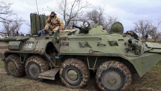 A Ukrainian soldier sits on a military vehicle at a checkpoint at the road near a Crimea region border. 