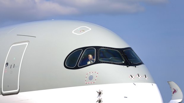 A pilot uses a smartphone to take a photograph from the cockpit of a Qatar Airways Airbus A350 aircraft.