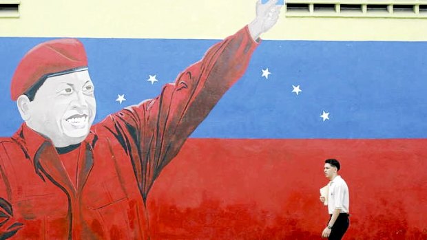 A man walks past a mural of Venezuelan President Hugo Chavez.