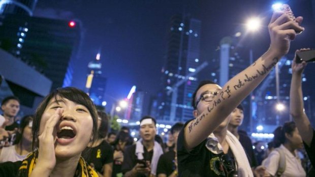 Student protesters chant pro-democracy slogans and shine their mobile phones during evening speeches at a protest site in Hong Kong.