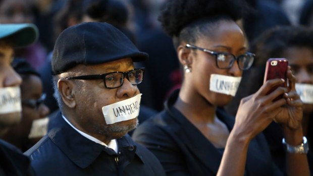 George Henderson, left, professor emeritus, joins hundreds of students at the University of Oklahoma to protest a fraternity's racist comments in Norman, Oklahoma. 