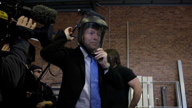 Strange work choice ... Tony Abbott dons safety equipment on a photo opportunity visit to Capital Doorworks yesterday.