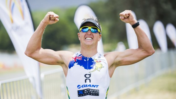 Winners are grinners: Ben Allen celebrates crossing the finish line as the winner of Canberra's inaugural T3X Endurance Triathlon on Sunday.