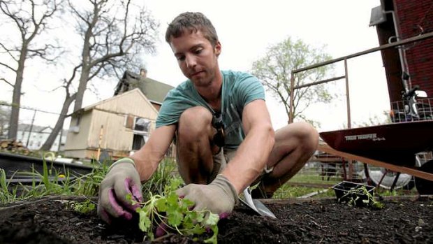 Darin McLeskey plants a vegetable garden in the back yard of one of the properties he purchased for bargain price and plans on refurbishing in Detroit, Michigan.