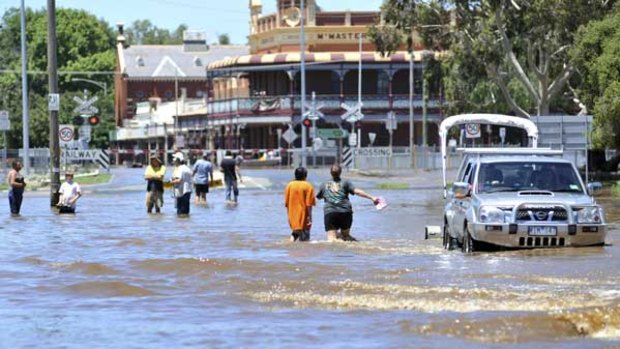 Residents wade through the main street of Rochester as the Campaspe River reached a record 9.15 metres yesterday afternoon, inundating 80 per cent of the town.