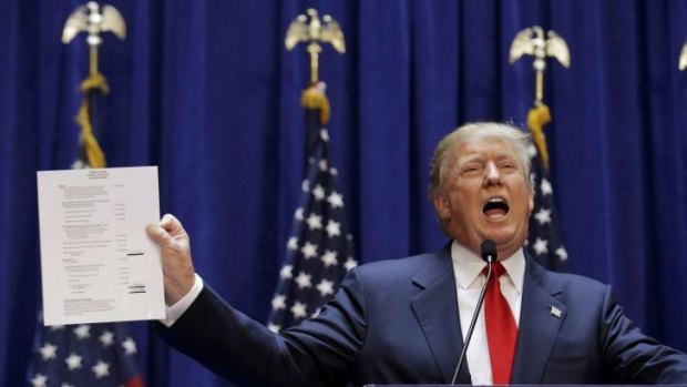 U.S. Republican presidential candidate, real estate mogul and TV personality Donald Trump holds up a financial statement showing his net worth.
