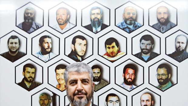 The wall of 'martyrs' ... Hamas leader Khalid Mishal stands before a mural of 20 slain Hamas leaders and operatives in his office in Damascus.