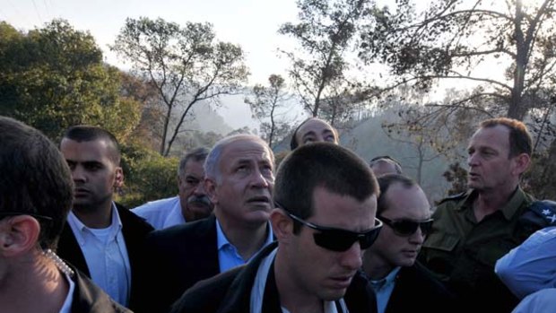 Hope from the sky ... Benjamin Netanyahu looks to the sky to watch a plane dropping fire-retardant chemicals on the fire at Mount Carmel.