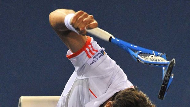 Marcos Baghdatis smashes an already destroyed racket in frustration during his match against Stanislas Wawrinka.
