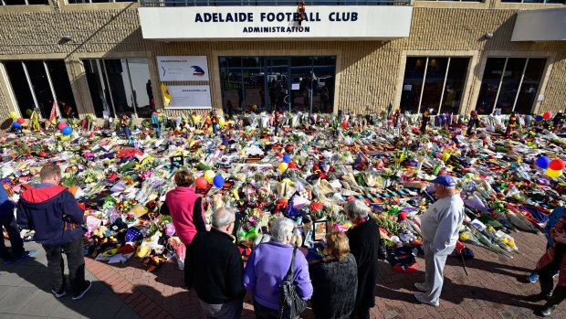 Tragedy: Supporters gathered in large numbers to mourn the death of Phil Walsh at the Adelaide Crows headquarters a year ago.