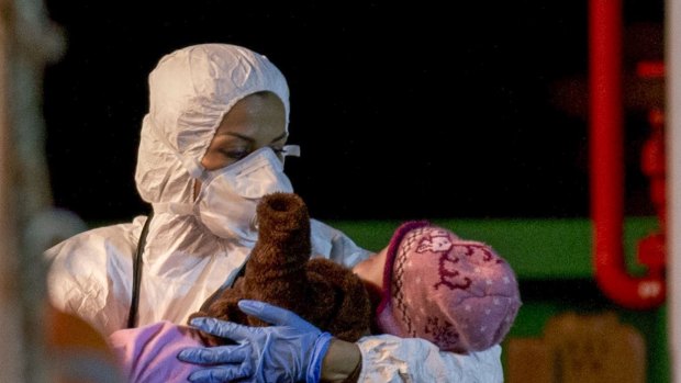 A rescuer cradles a child in  Pozzallo.