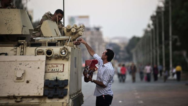 An Egyptian man offers some dates to a soldier outside the presidential palace.