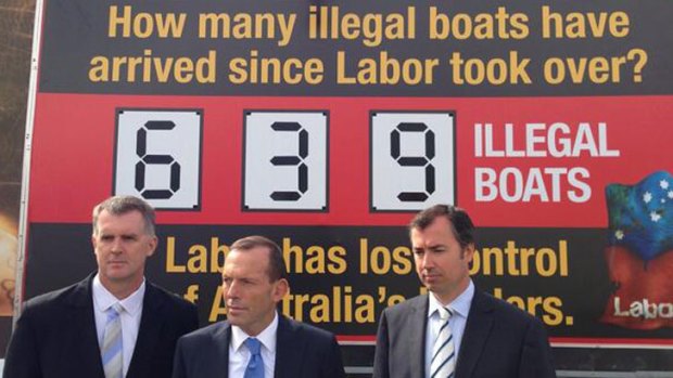 Opposition Leader Tony Abbott, centre, with a tweeted picture of the billboard on asylum seeker boat arrivals he re-launched in Perth.