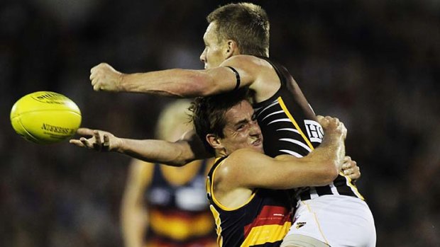 Over the top: Hawthorn midfielder Sam Mitchell dishes off a handball despite a strong tackle by Crow Richard Douglas.
