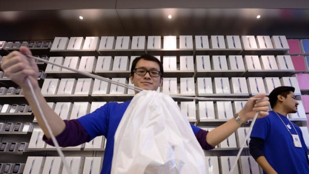 A worker at the Hong Kong Apple Store ties up a shopping bag with a new iPad.