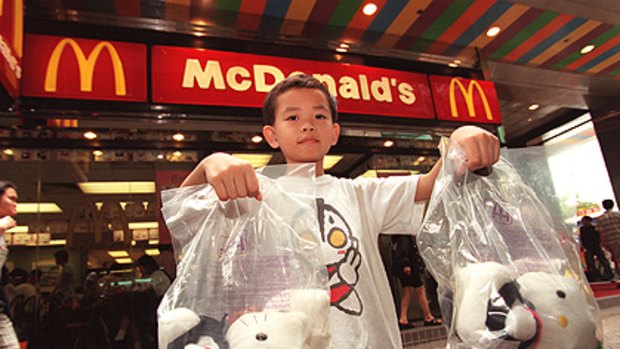 A boy displays giveaway Hello Kitty dolls used in a McDonald’s promotion in Hong Kong.