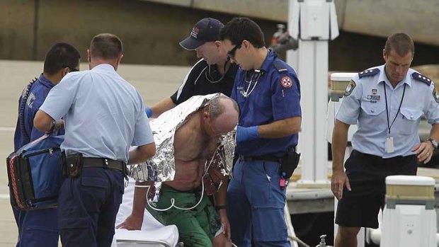 Saved ... Paramedics assist one of the men at NSW police marine area command in Balmain today.