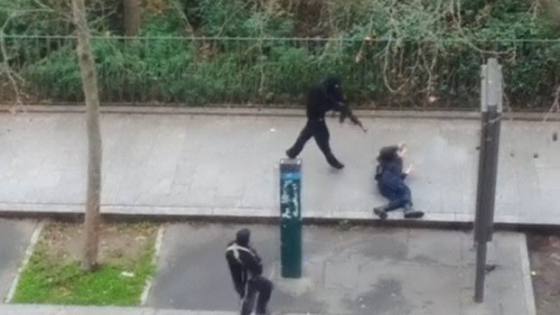 A hooded gunmen stands over a wounded police officer before executing him at point-blank range in this still from an amateur video capturing the terrorist attack.