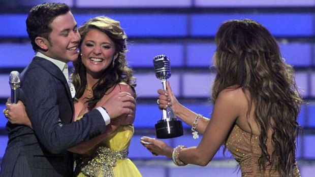 Winner ... Scotty McCreery, left, hugs finalist Lauren Alaina as Jennifer Lopez hands him his trophy.