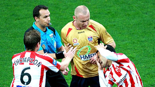 Newcastle's Jobe Wheelhouse clashes with Aziz Behich of the Melbourne Heart at AAMI Park last night. Wheelhouse was sent off, but within 11 minutes Newcastle led 2-0.