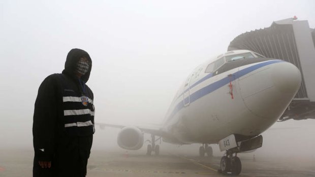 A man stands next to an aeroplane under heavy smog in Harbin.