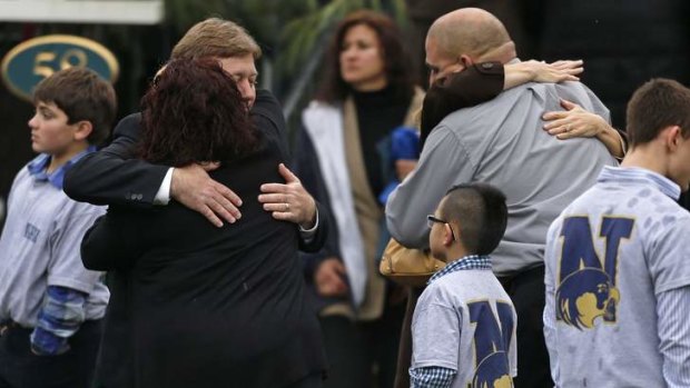 Families embrace while surrounded by children wearing Newtown school shirts outside the funeral for six-year-old shooting victim Jack Pinto.