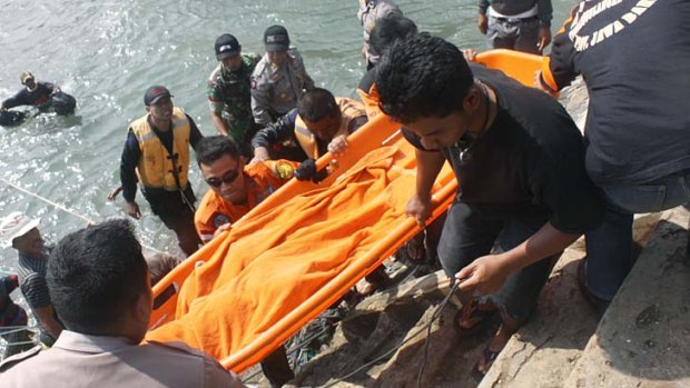Tragedy: Rescuers carry the body of a victim killed after a boat carrying asylum seekers sank off Java island.