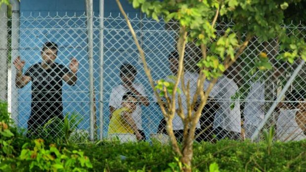 Asylum seekers sit behind the wire of the Manus Island detention centre.