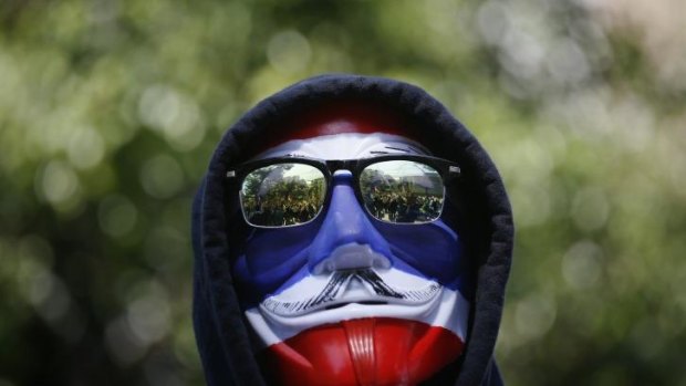 An anti-government protester wears a mask in national colours in Thailand