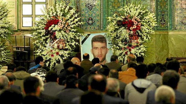 Men gather in front of a large photo of killed asylum seeker Reza Barati during the memorial service, held at the Al-Mahdi mosque in the Nabard neighbourhood in South East Tehran, Iran.