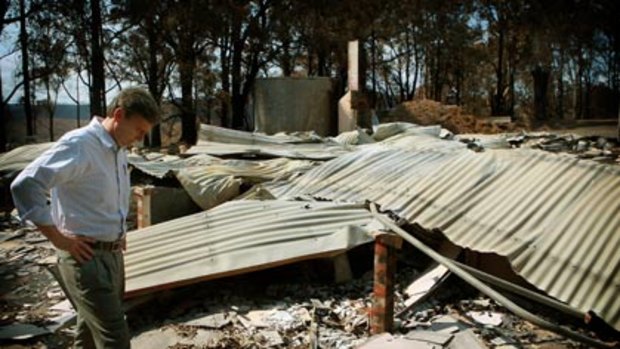 Ten days after the Black Saturday bushfires, Premier John Brumby inspects the remains of the Callgnee community hall.