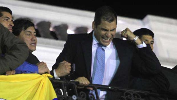 Rafael Correa hails his supporters from the balcony of the presidential palace after he was rescued by the army.