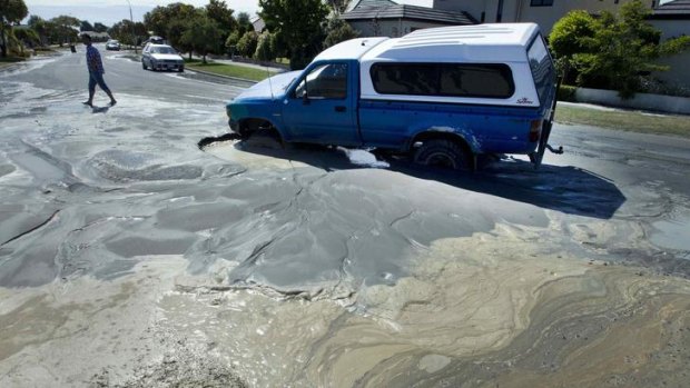 Sewage spreads on a Parklands street as liquefaction from the earthquake causes a car to become trapped in a sinkhole.