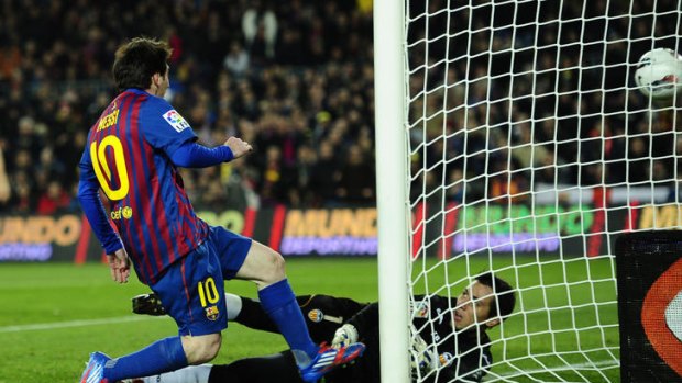 Lionel Messi scores a goal past Valencia's goalkeeper Diego Alves,.