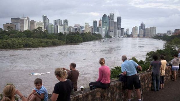 Flood watchers observe the passing stream above the Brisbane River,filled with all manner of dangerous items - above and below water.