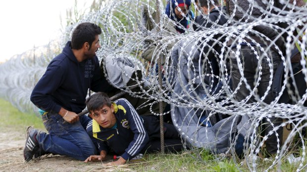 Syrian migrants cross under a fence into Hungary at the border with Serbia, near Roszke on Wednesday.