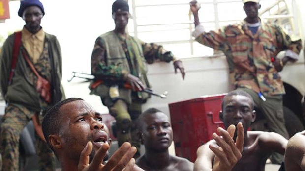 Staying put ... a man captured by Alassane Oattara's troops pleads his innocence at a checkpoint outside Abidjan.