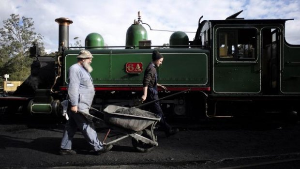 Railway workers carry a wheelbarrow full of ash after cleaning out the smokebox of locomotive 6A.