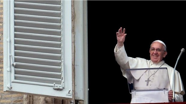 Pope Francis waves to the crowd from the window of the apostolic palace overlooking St Peter's square.