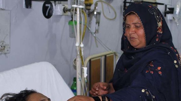 An unidentified relative of Shumaila Kanwal, the widow of a Pakistani man allegedly shot and killed by a US official, helps her to drink water at a local hospital in Faisalabad.