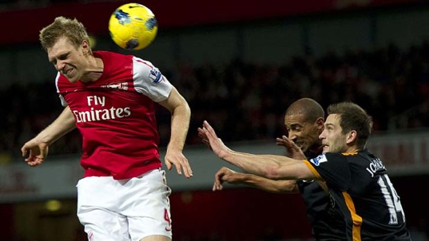 Arsenal's German player Per Mertesacker (L) heads the ball under a challenge from Wolverhampton Wanderers'  Roger Johnson (2nd R) and Karl Henry (R).