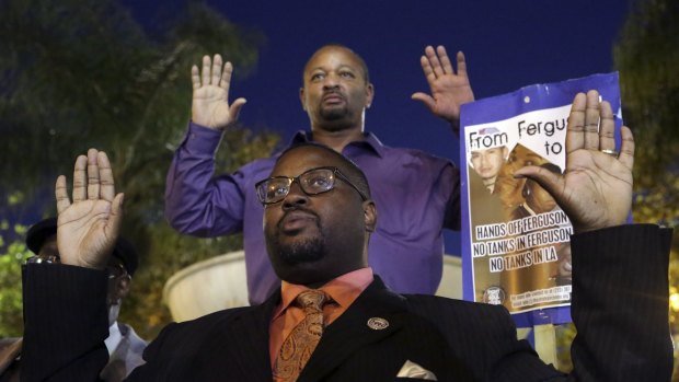Reverend K.W. Tulloss and community activist Najee Ali hold up their arms during a demonstration in Los Angeles following the grand jury decision in the shooting of Michael Brown.
