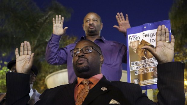 Reverend K.W. Tulloss and community activist Najee Ali hold up their arms during a demonstration in Los Angeles following the grand jury decision in the shooting of Michael Brown.