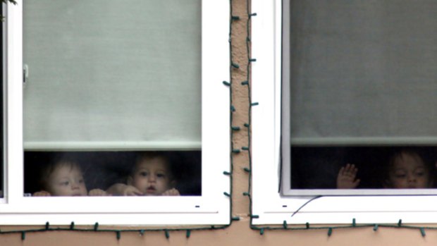 Children peer from a window in Nadya Suleman's home on the day of the octuplets' first birthday.