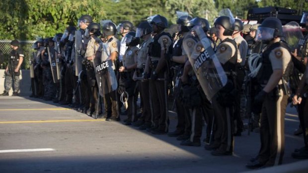 Police officers keep watch while demonstrators (not pictured) protest the death of black teenager Michael Brown in Ferguson, Missouri on Monday.