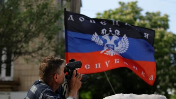 A Pro-Russian rebel looks through binoculars as the Donetsk Republic flag waves overhead at a rebel position in Slaviansk in East Ukraine.