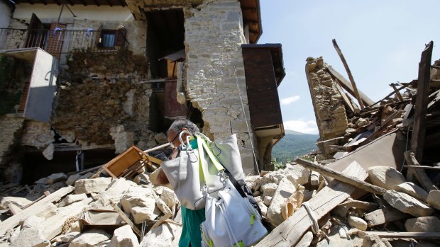 A man walks away after getting his personal belongings from his house in Villa San Lorenzo, near Amatrice.