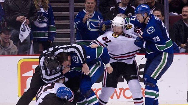 Taking control: Assistant referee Jean Morin grabs Vancouver player Kevin Bieksa in a headlock as the Canucks and Chicago Blackhawks slug it out during game five of the Stanley Cup playoffs.