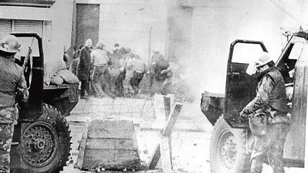 Soldiers take cover behind cars while dispersing rioters with tear gas in Londonderry in 1972.